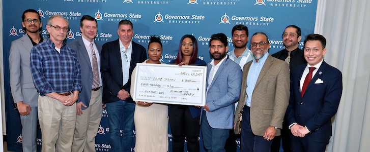 A group of people standing together and holding a check